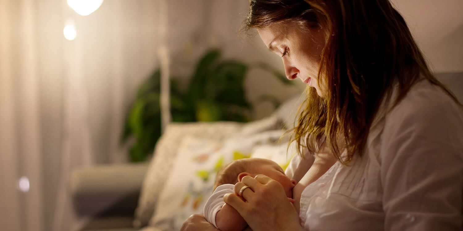 Mother sitting on sofa breastfeeding her baby