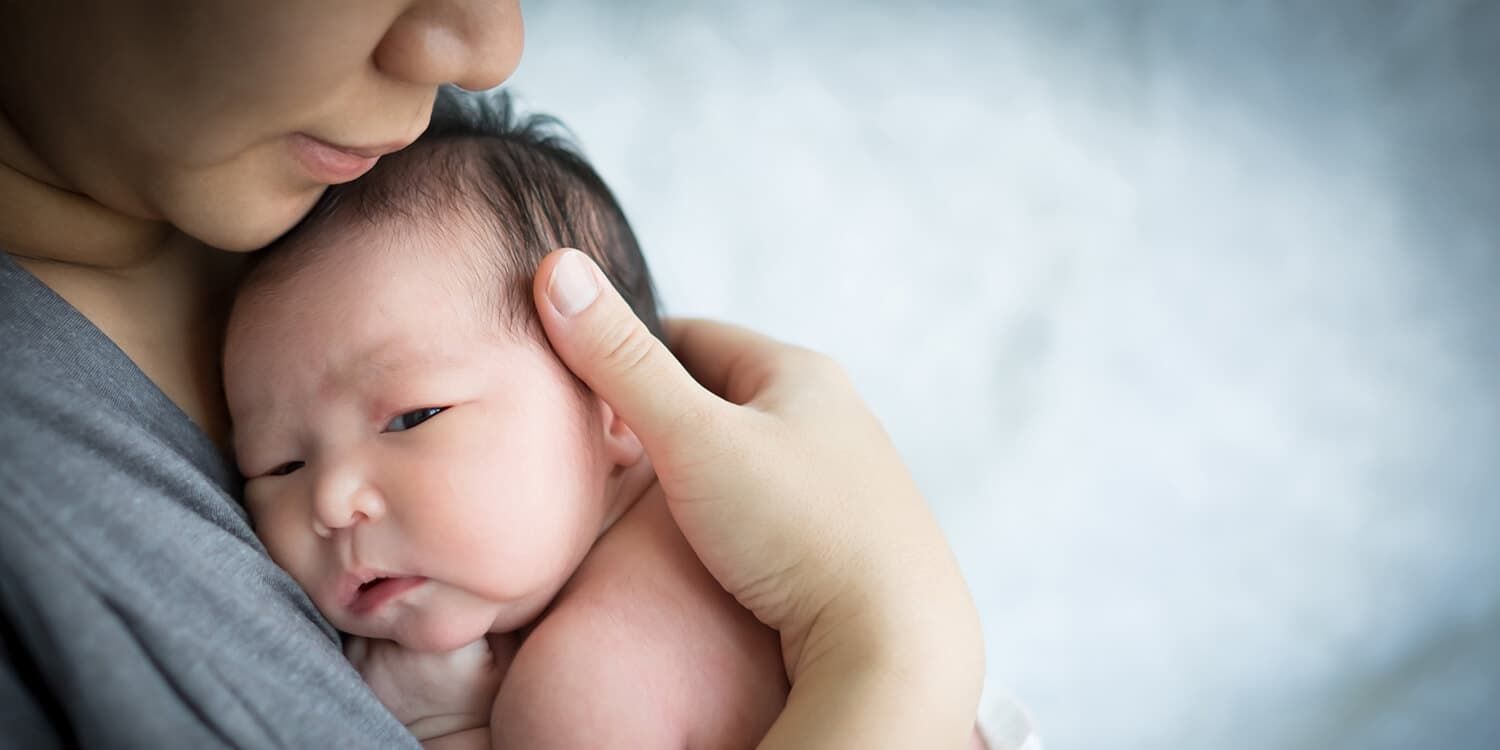 A mother calming her baby and holding it in her arms.