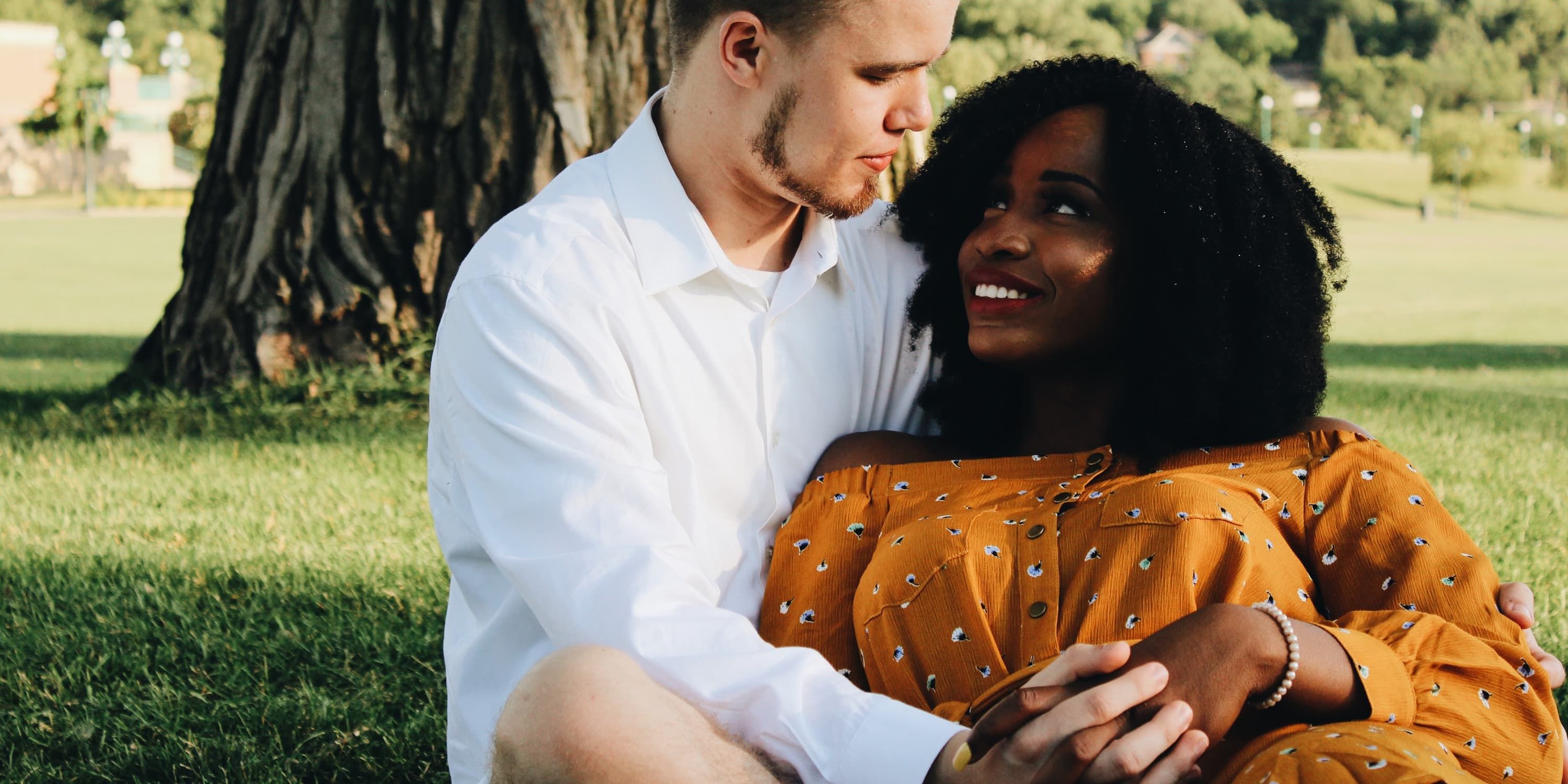 A man cuddles a woman in the park