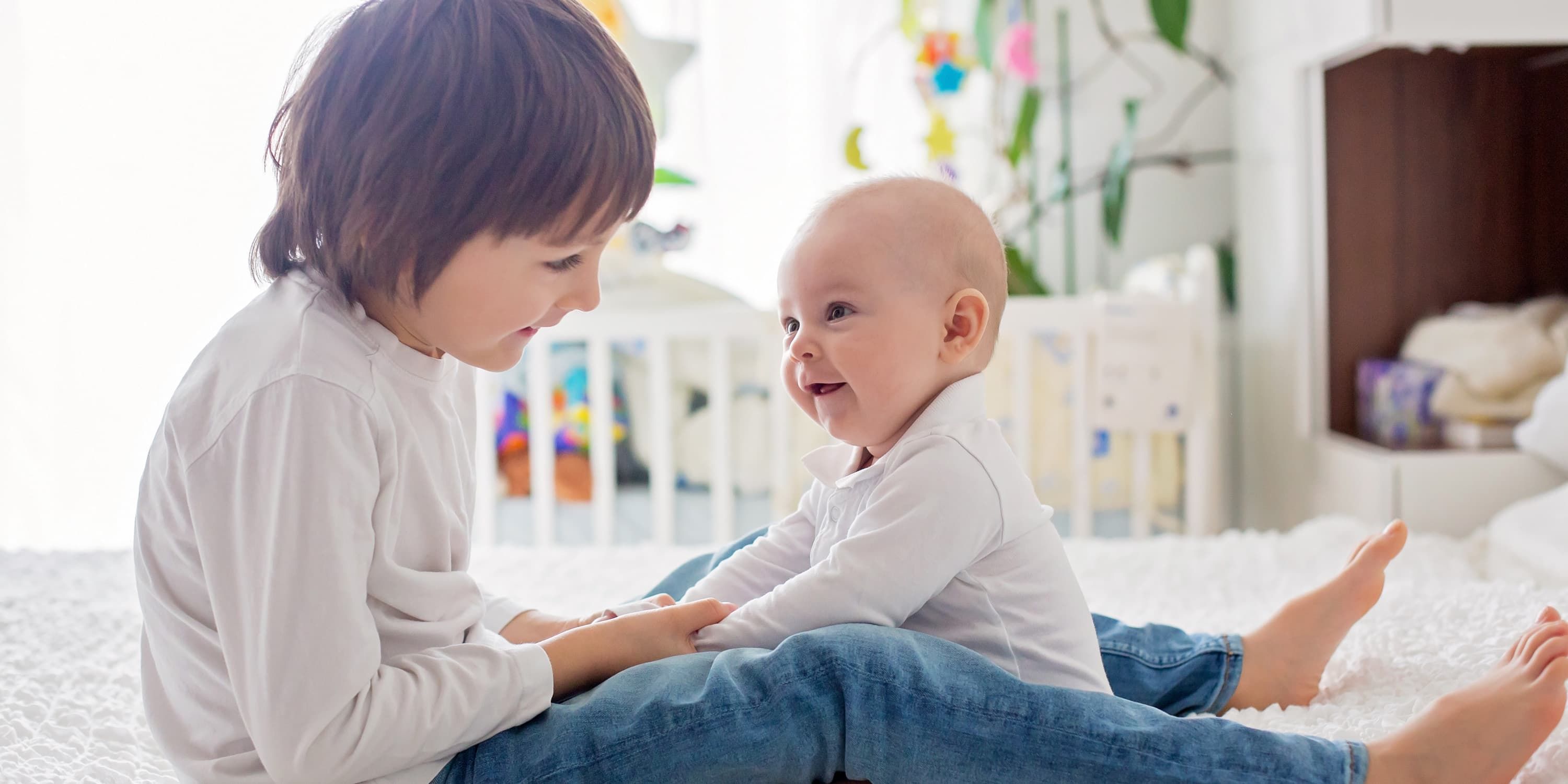 Geschwisterkind spielt mit Baby auf dem Fußboden