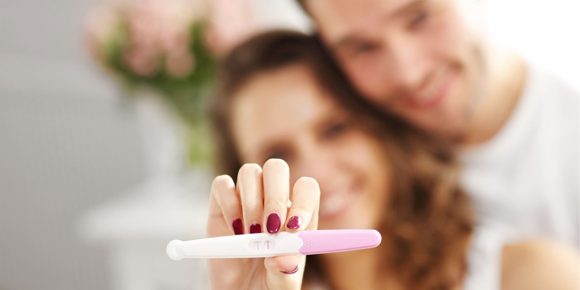 casal feliz com teste de gravidez no quarto 