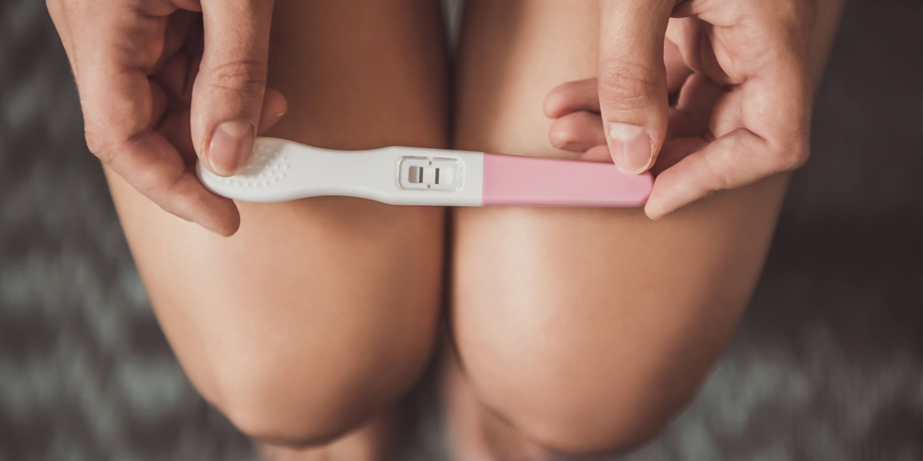 Une jeune femme tient dans ses mains un test de grossesse. 