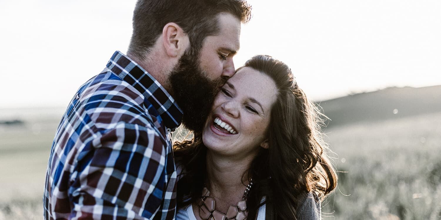 man kissing woman in grass area