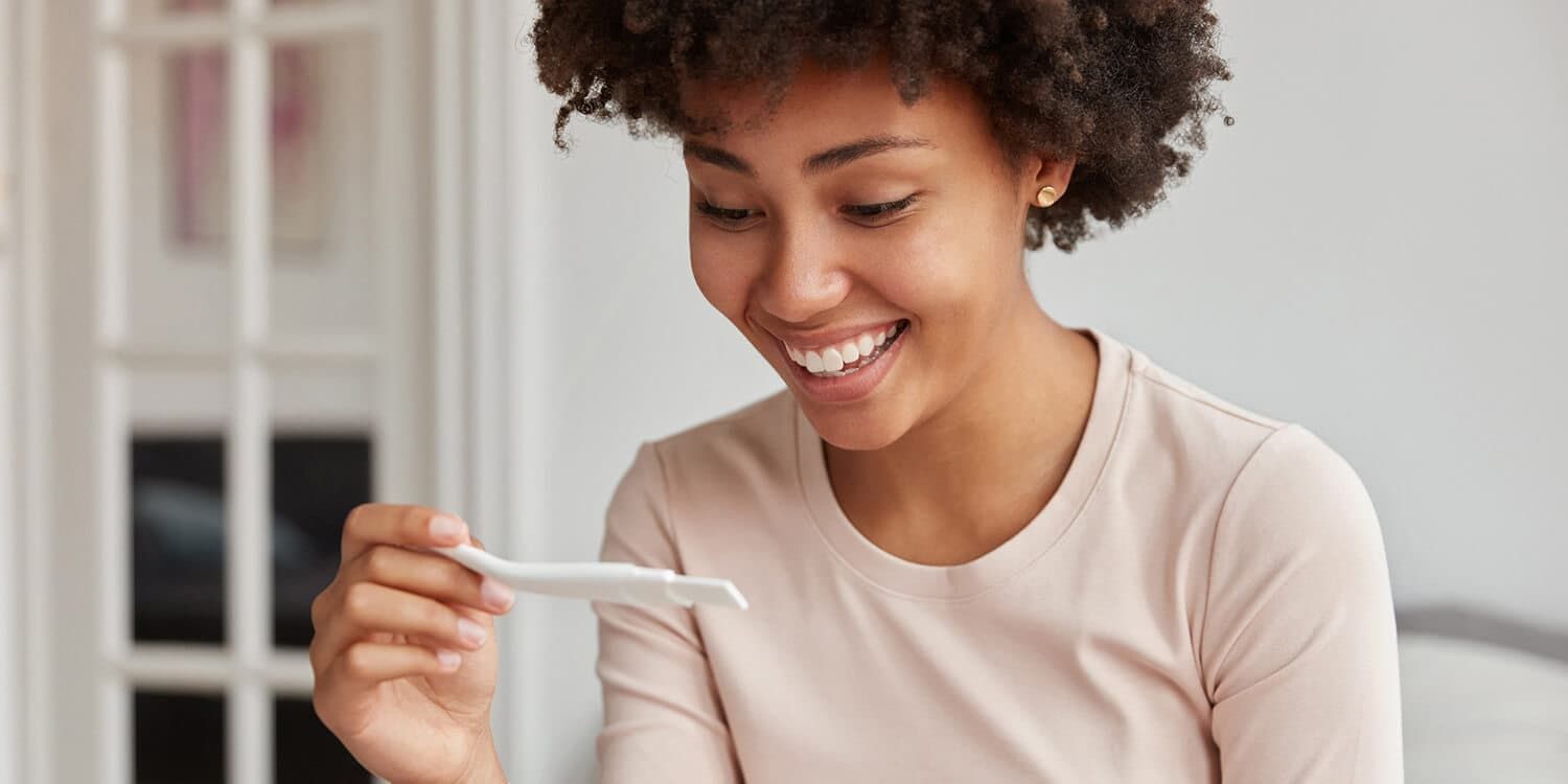 Happy young woman with pregnancy test.