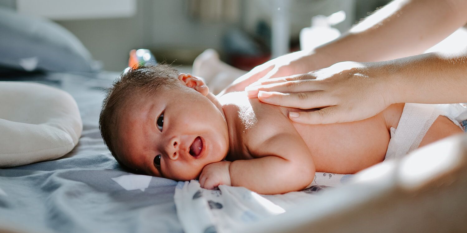 Mother gently massages her baby on the back