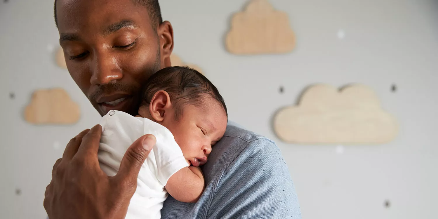 Vater wiegt ein neugeborenes Kind in den Schlaf