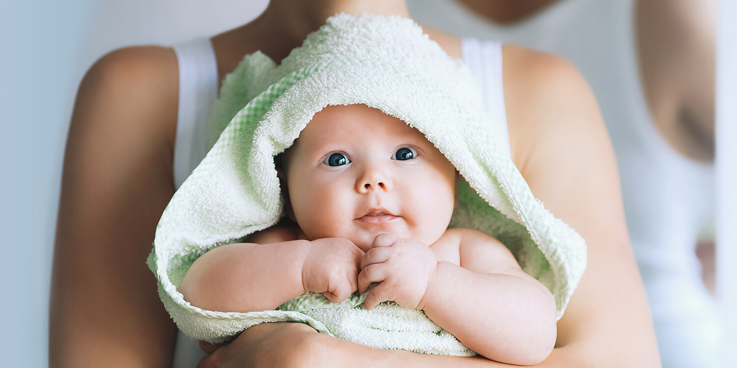 Mother hugs her baby after bath, baby is wrapped in towel