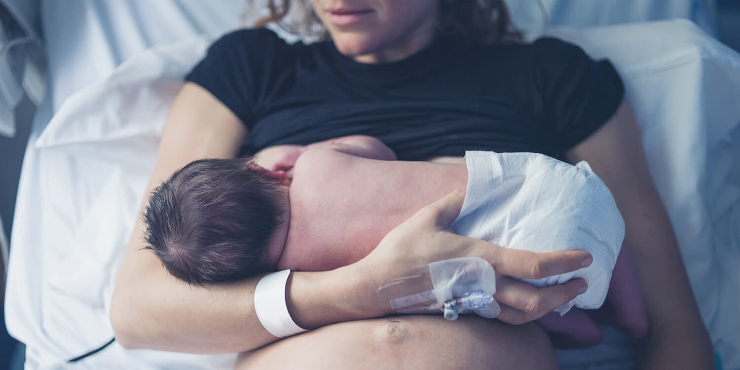 Mother breastfeeds her baby in hospital after birth.